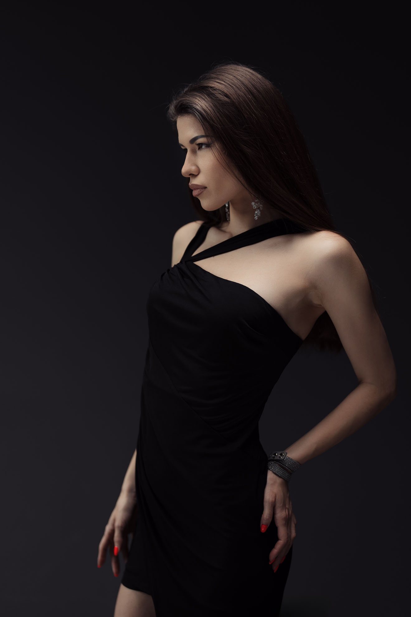 Elegant woman in black dress on dark background Side profile of a graceful young woman wearing a black dress, featuring her poised demeanor against a dark background. This image encapsulates elegance, beauty, and a serene atmosphere.